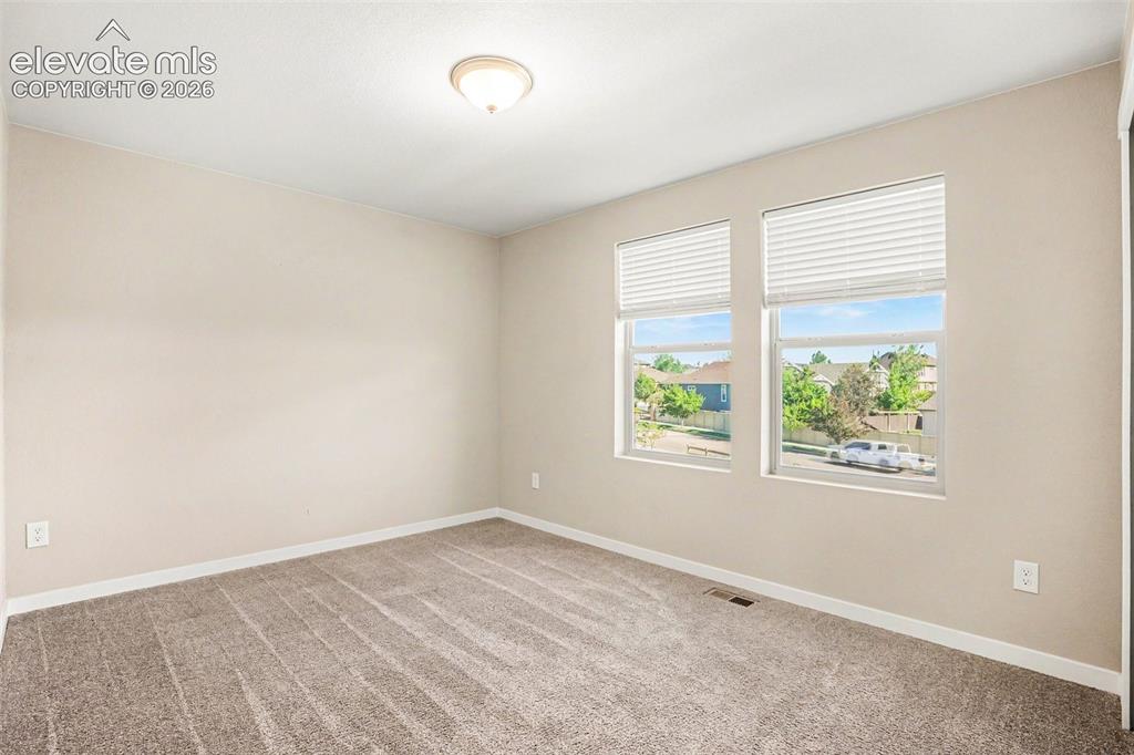 Image 17 of 27: Spacious interior room with light grey wall paint and grey carpet flooring