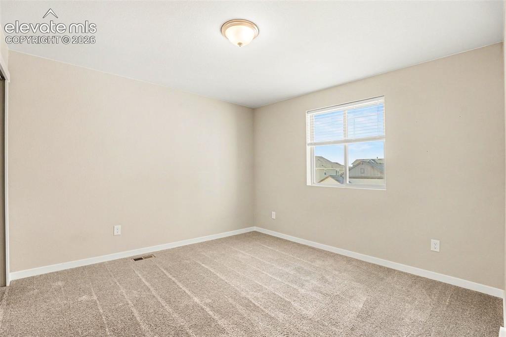 Image 18 of 27: Spacious carpeted room featuring a ceiling fan with light fixture, multiple