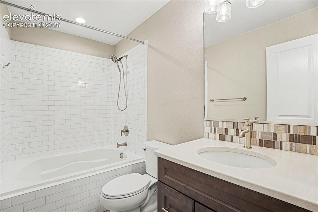 Image 20 of 27: Bathroom featuring dual vanity with stone countertops, herringbone wood-fin