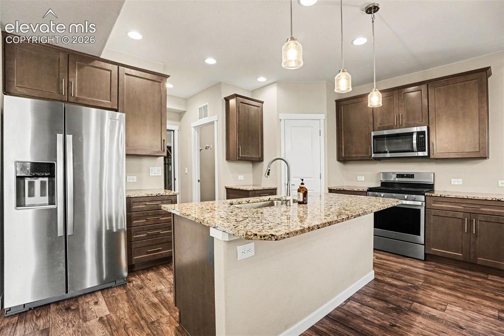 Image 9 of 27: Spacious living area featuring wood-finish flooring, a fireplace with a her