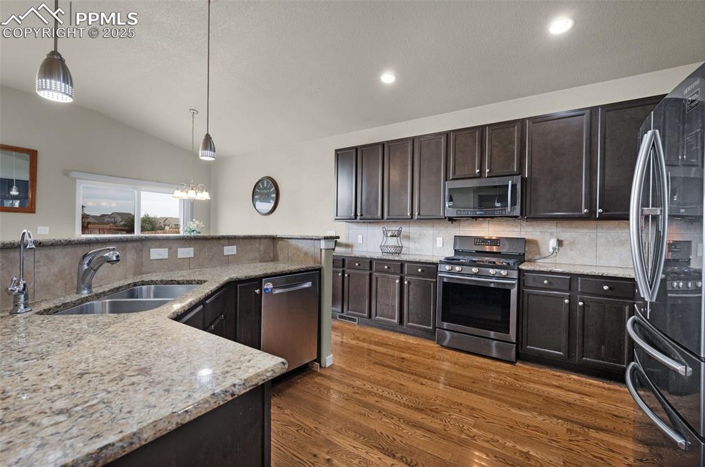 Image 12 of 31: Kitchen featuring appliances with stainless steel finishes, a sink, dark wo