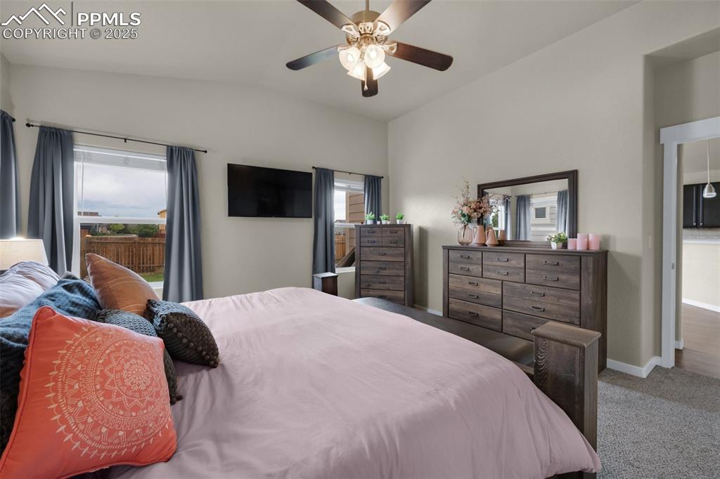 Image 16 of 31: Carpeted bedroom with lofted ceiling, baseboards, and a ceiling fan