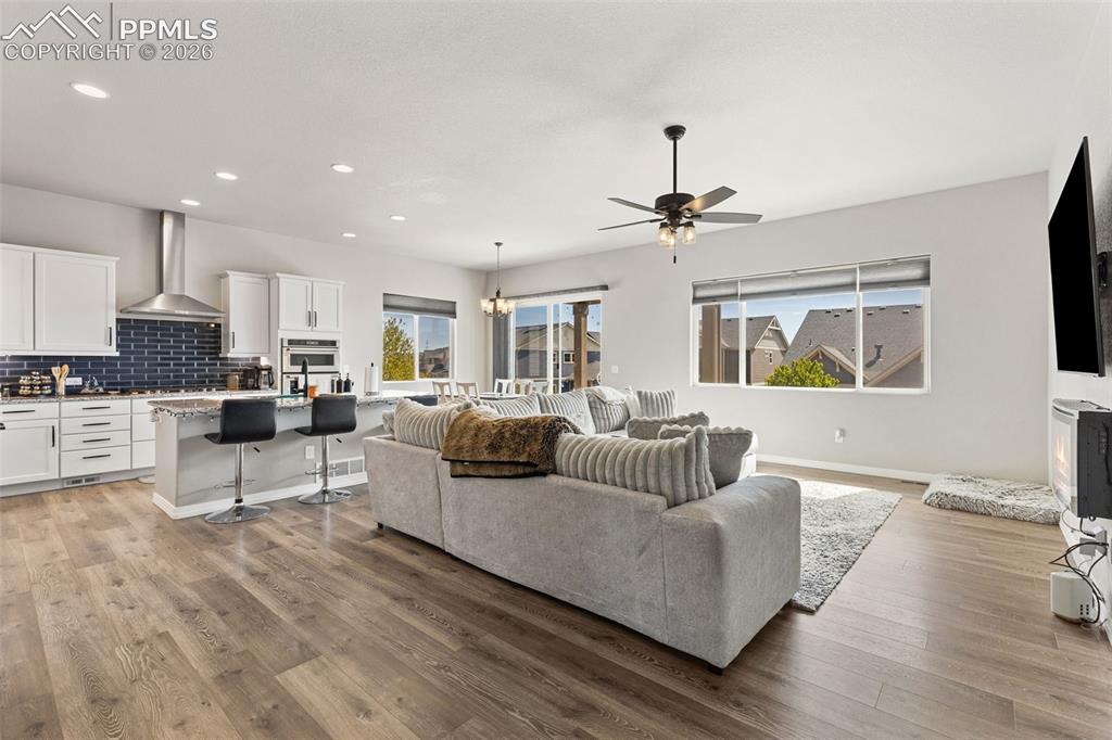 Image 10 of 44: Open-concept living space featuring wood-finish flooring, a contemporary ki