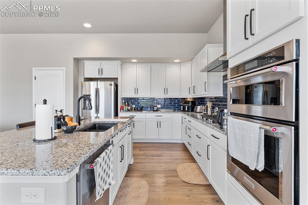 Image 15 of 44: Contemporary kitchen featuring white cabinetry, granite countertops, a dark