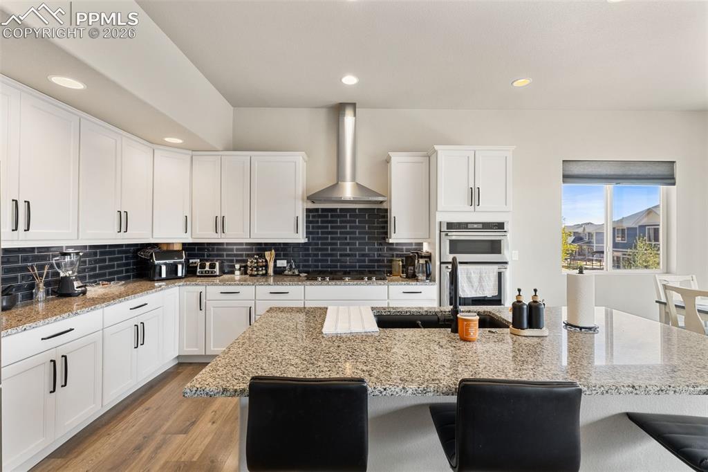 Image 18 of 44: Contemporary kitchen featuring white cabinetry, dark subway tile backsplash