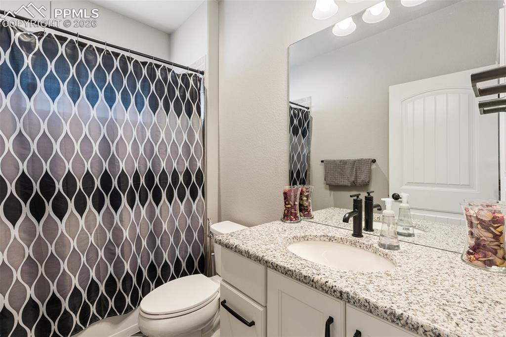 Image 19 of 44: Bathroom vanity featuring a granite countertop, undermount sink, and matte 