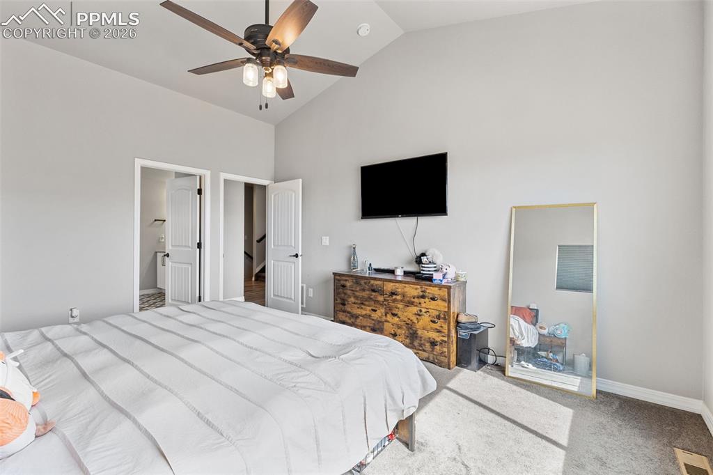 Image 27 of 44: Bedroom featuring a vaulted ceiling and a wood-finish ceiling fan with inte