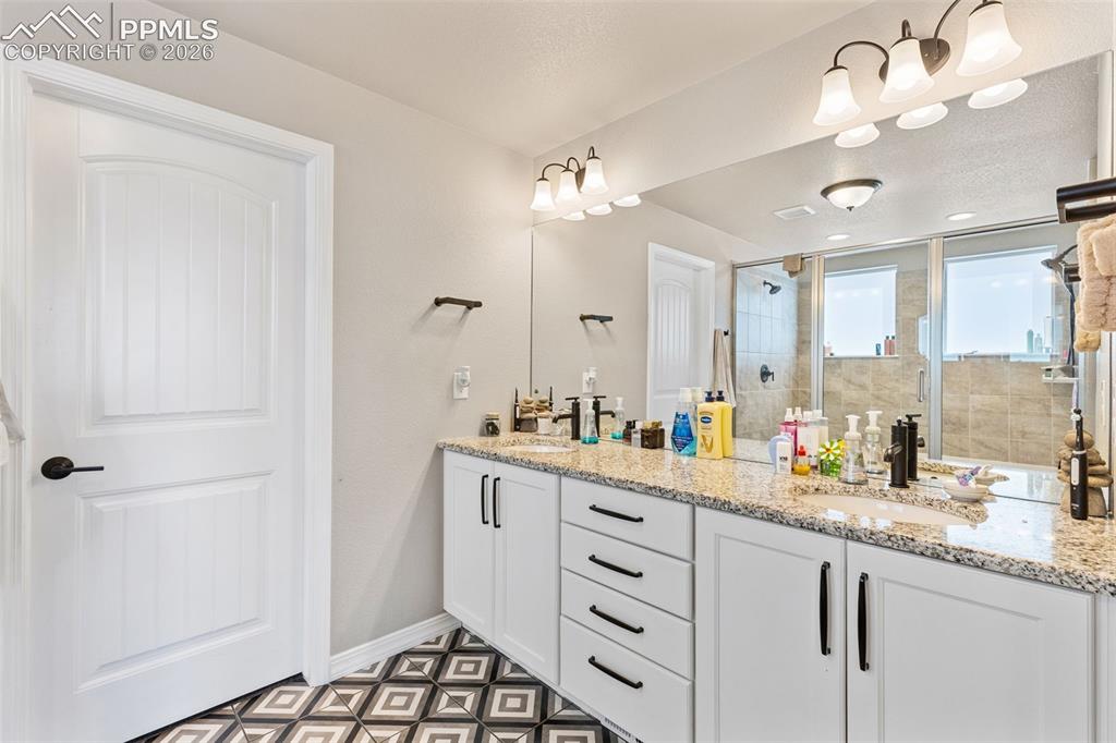 Image 28 of 44: Dual vanity featuring granite countertops and white cabinetry with matte bl