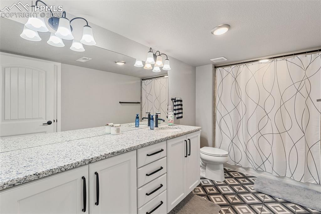 Image 35 of 44: Spacious bathroom featuring a double vanity with white cabinetry and black 