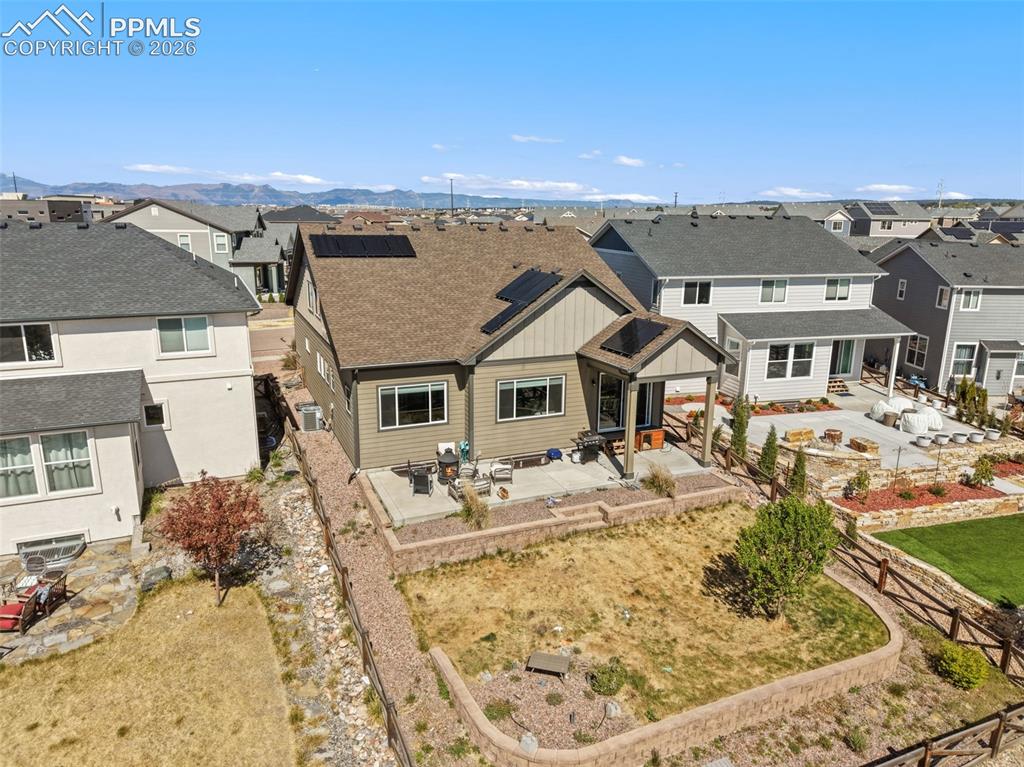 Image 41 of 44: Rear exterior featuring a covered patio, multiple windows, and solar panels