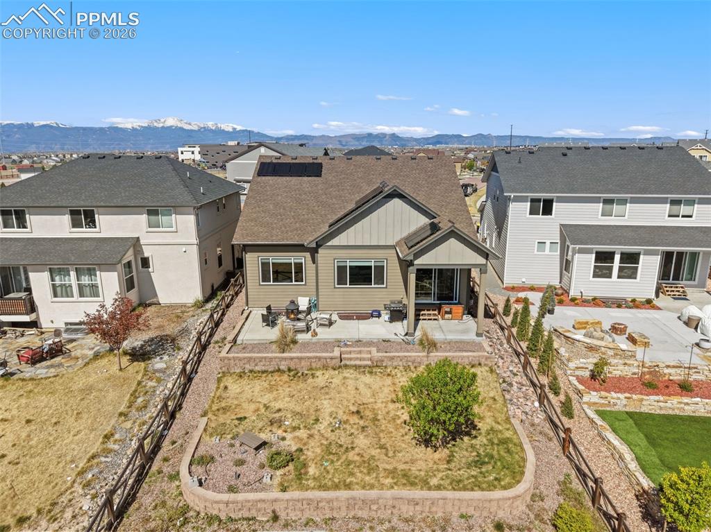 Image 42 of 44: Rear exterior featuring a covered patio, tiered retaining walls, and a fenc