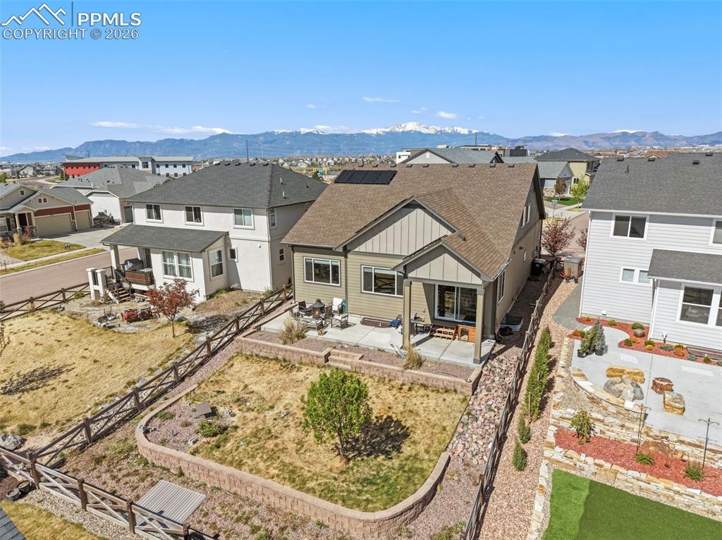 Image 43 of 44: Rear exterior featuring a covered patio, tiered landscaping with retaining 