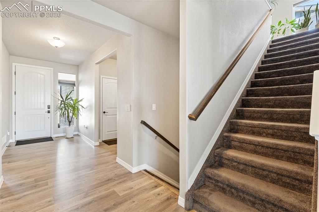 Image 9 of 44: Foyer featuring wood-finish flooring, a white paneled front door, and a car