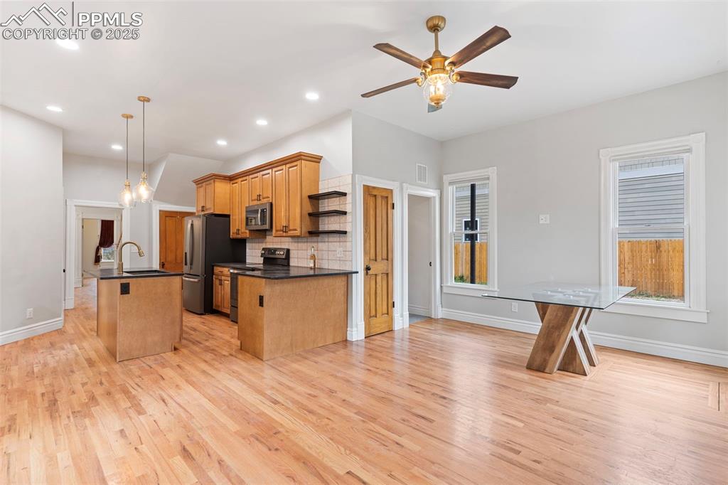Image 10 of 36: Kitchen with tasteful backsplash, hanging light fixtures, a center island w