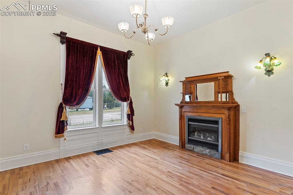 Image 13 of 36: Unfurnished living room with light wood-style floors, a chandelier, and a g
