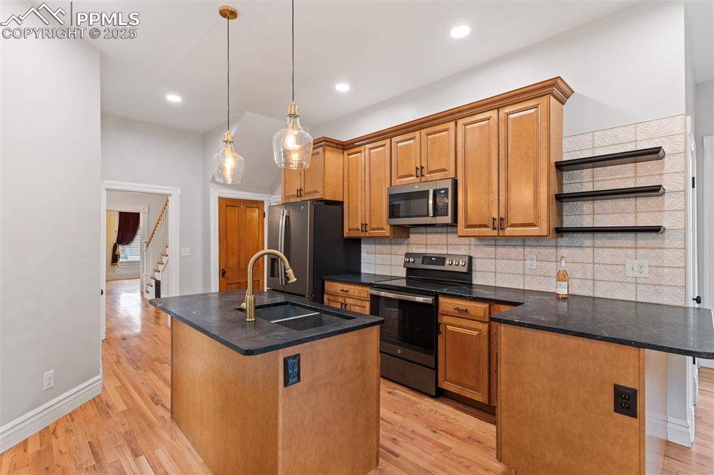 Image 2 of 36: Kitchen with backsplash, appliances with stainless steel finishes, a center