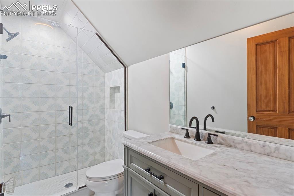 Image 6 of 36: Bathroom featuring a shower stall, vanity, and vaulted ceiling