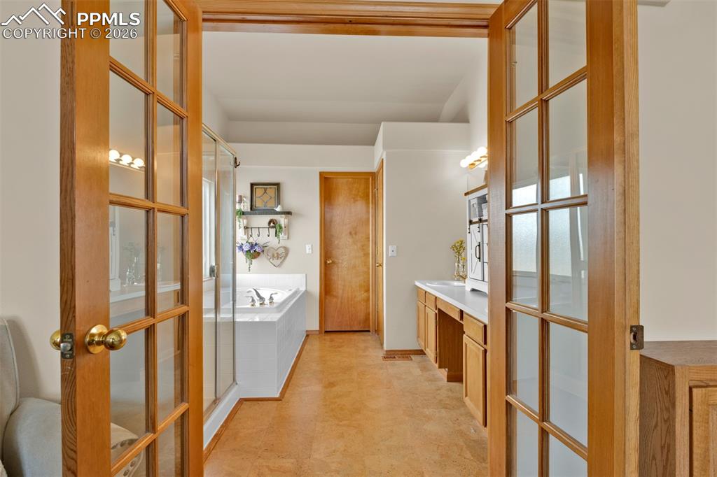 Image 23 of 50: French doors leading to the primary bathroom with seperate tub and shower,