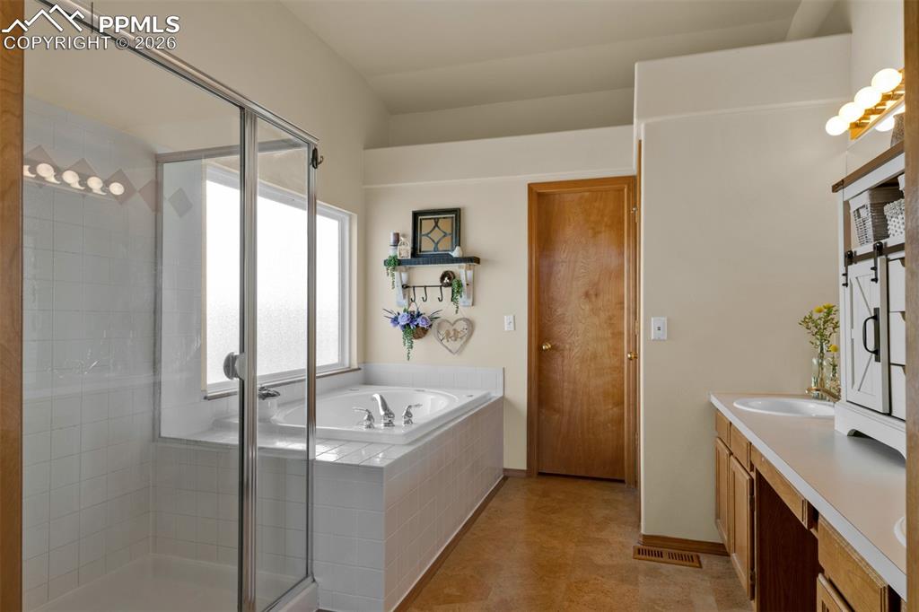 Image 24 of 50: French doors leading to the primary bathroom with seperate tub and shower,