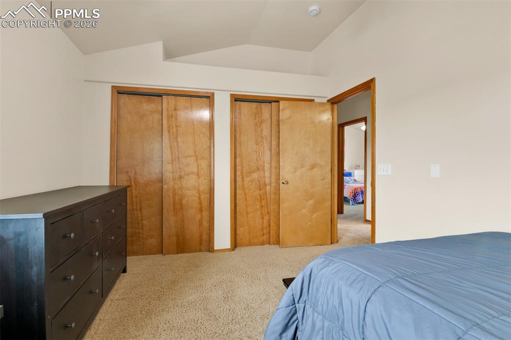 Image 27 of 50: Upstairs secondary bedroom #1 with vaulted ceilings, large closet and views