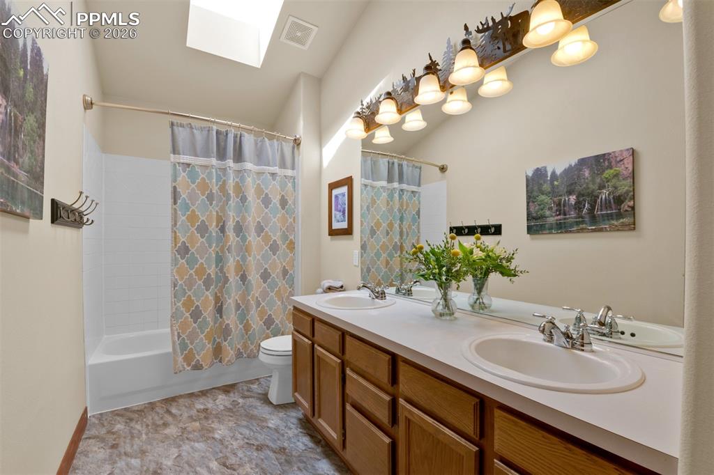 Image 28 of 50: Upstairs seconadry bathroom with dual vanities and skylight. Plenty of stor