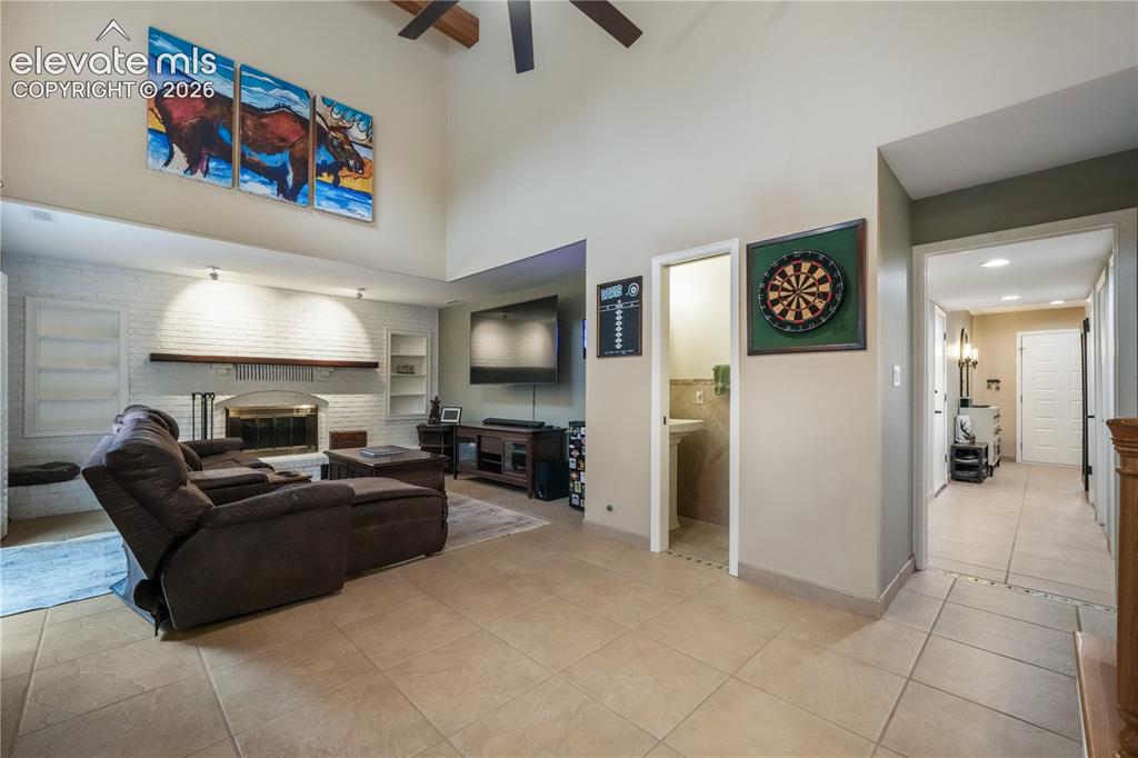 Image 25 of 50: Main level family room with gas fireplace, tile floors, built ins and acces