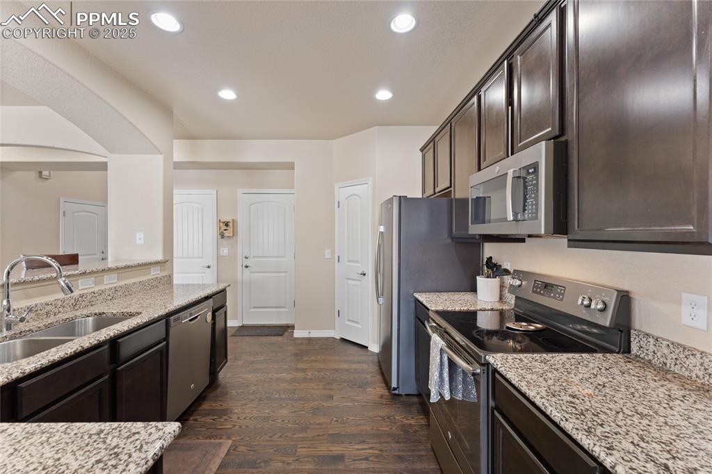 Image 12 of 38: Kitchen with slate steel appliances, granite counters, wood floors, pantry