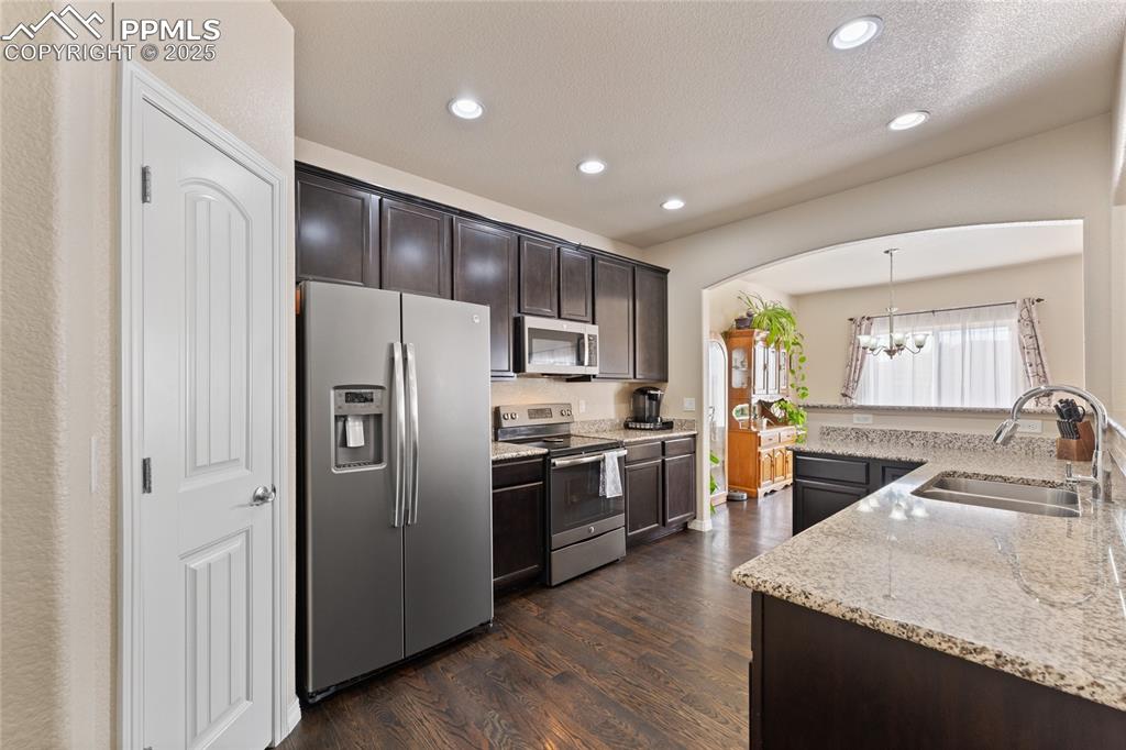 Image 13 of 38: Kitchen with slate steel appliances, granite counters, wood floors, pantry