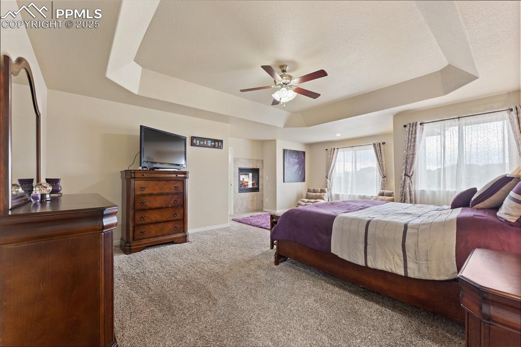 Image 18 of 38: Huge primary bedroom with a raised ceiling, double sided fireplace and sitt