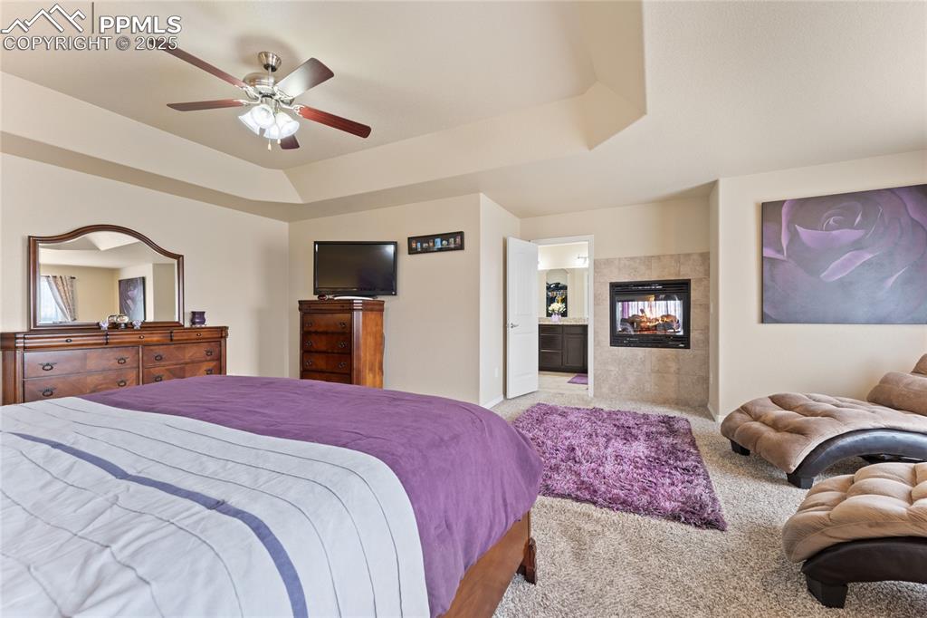 Image 20 of 38: Huge primary bedroom with a raised ceiling, double sided fireplace and sitt