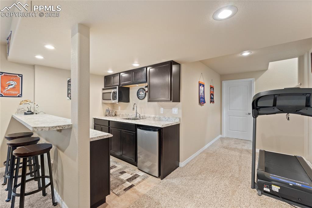 Image 30 of 38: Basement wet bar with SS microwave and mini refrigerator