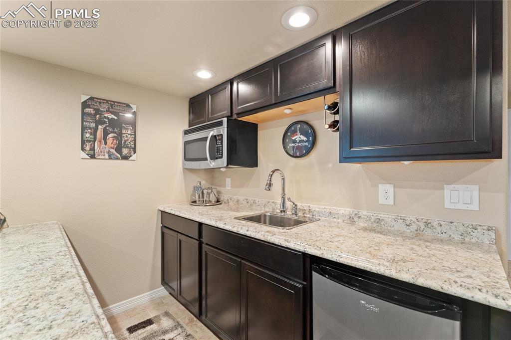 Image 31 of 38: Basement wet bar with SS microwave and mini refrigerator