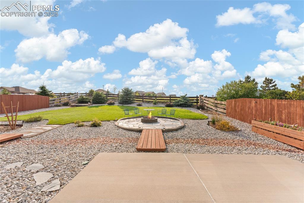 Image 37 of 38: Fenced backyard with a patio and an outdoor fire pit