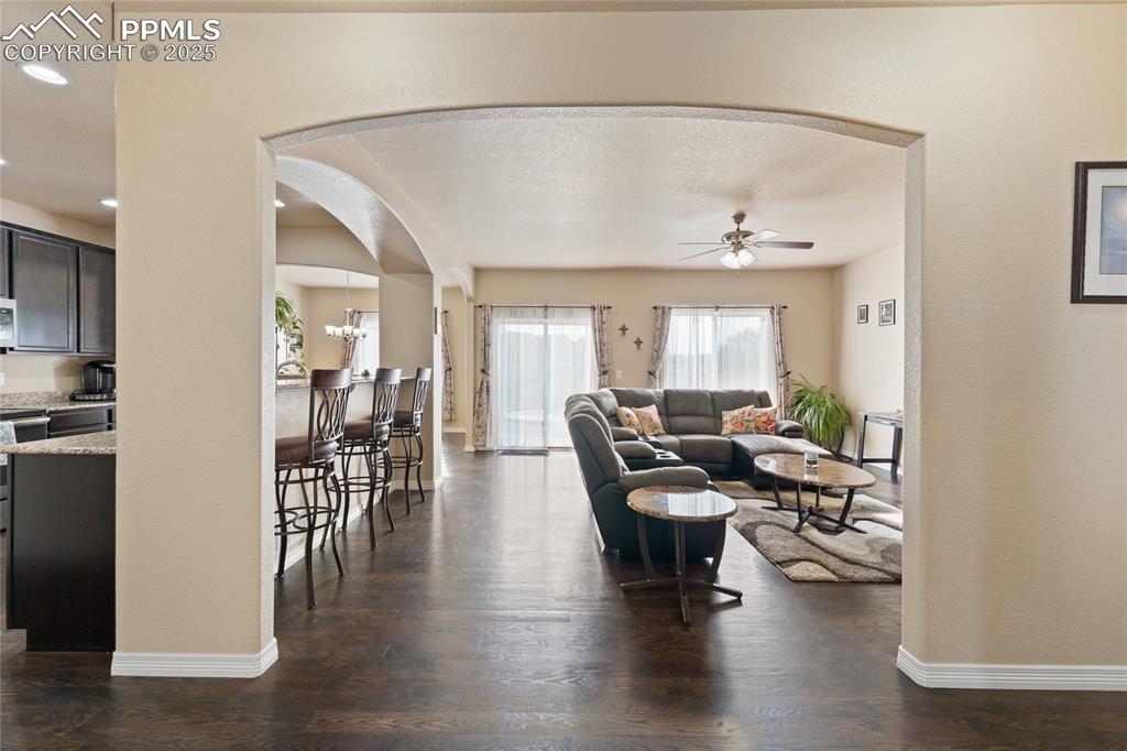 Image 6 of 38: Living room with arched walkways, wood floors, ceiling fan and gas fireplac