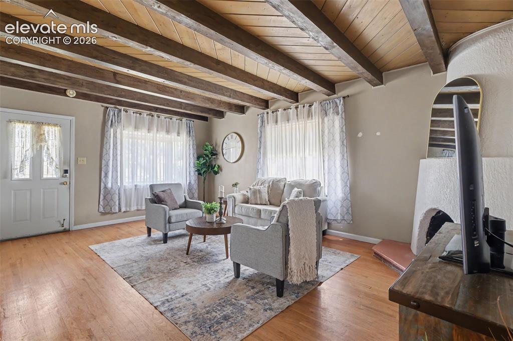 Image 3 of 36: Living room with fireplace and beamed ceiling.