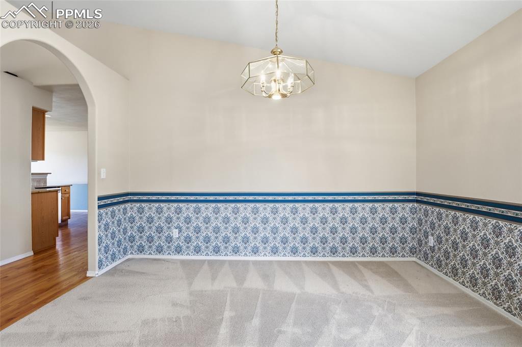 Image 18 of 50: Spare room with arched walkways, hanging lights, light colored carpet, wain