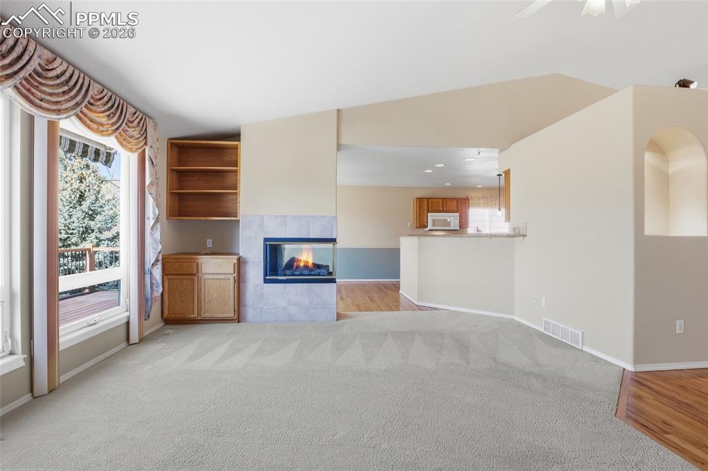 Image 21 of 50: Unfurnished living room with light colored carpet, a fireplace, vaulted cei