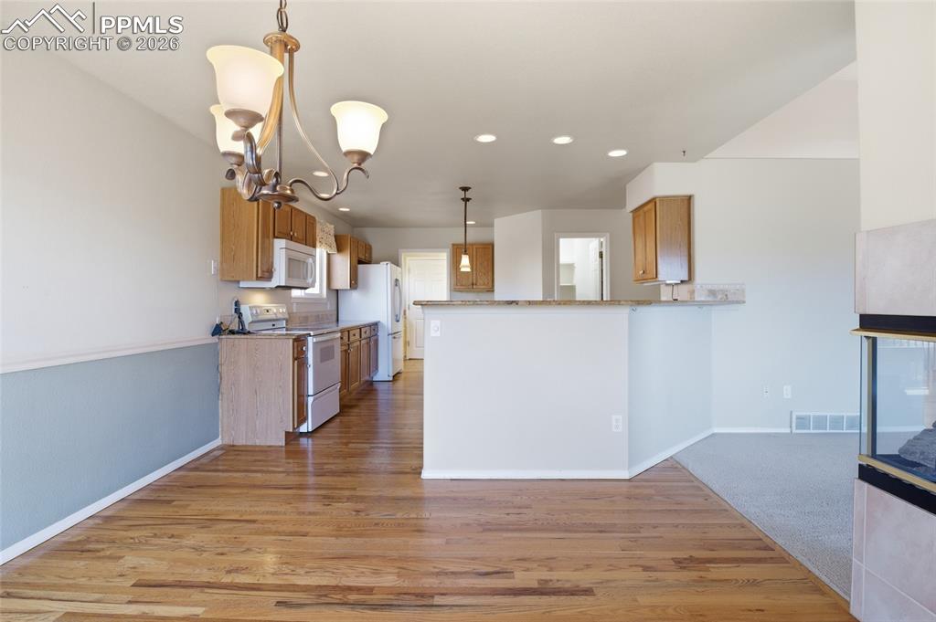 Image 24 of 50: Kitchen with wood finish cabinets, white appliances, a peninsula, light woo