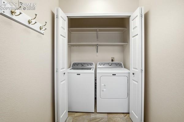 Image 31 of 50: Laundry area with washing machine and dryer and a textured wall