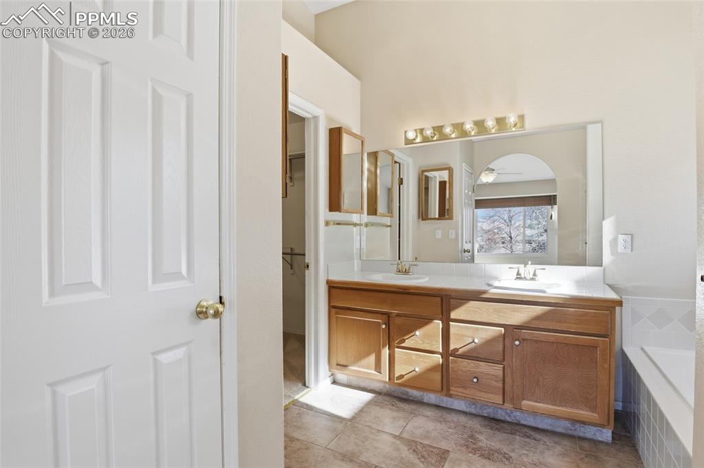 Image 35 of 50: Bathroom with double vanity, light tile patterned floors, a walk in closet,