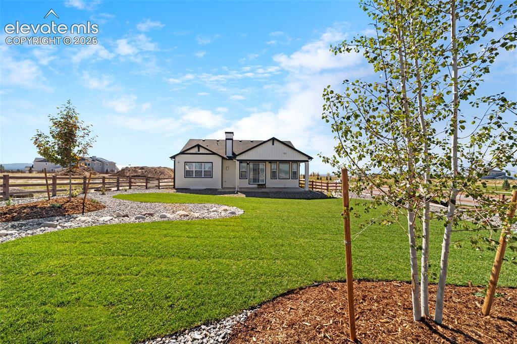 Image 14 of 38: Expansive backyard featuring a manicured lawn, established trees, and a dec