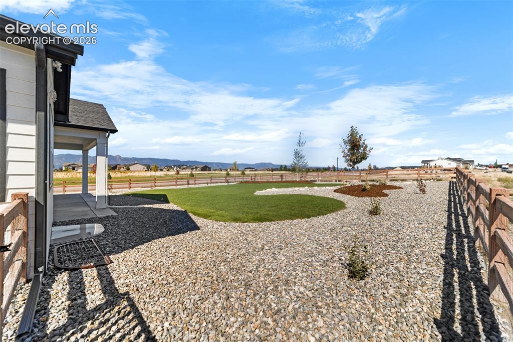 Image 17 of 38: Expansive backyard featuring a manicured circular lawn, natural rock landsc