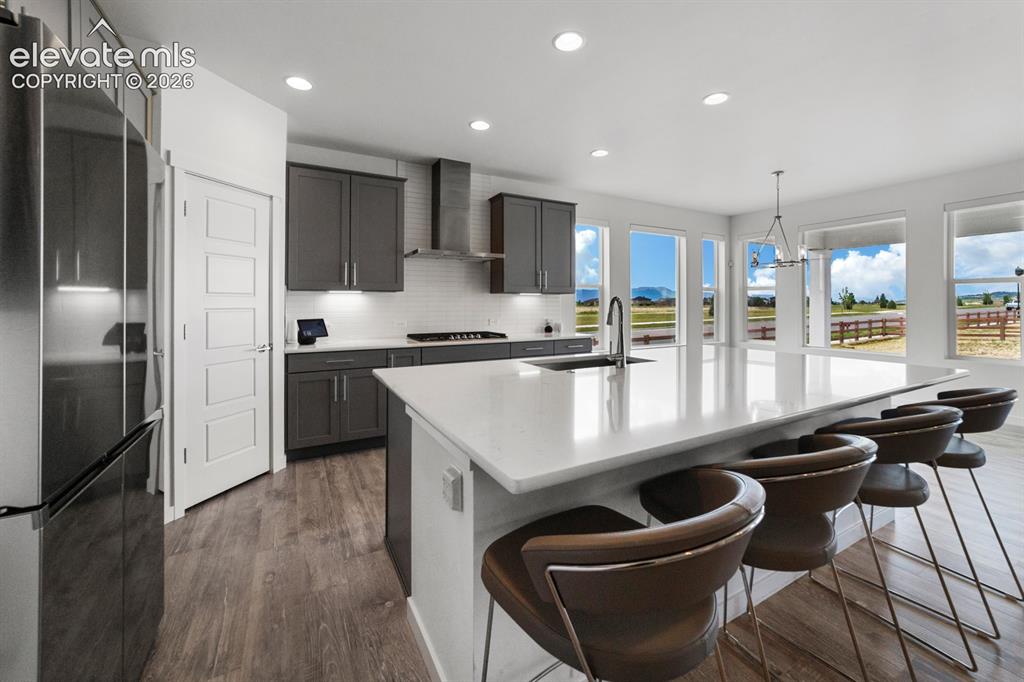 Image 2 of 38: Modern kitchen featuring a large island with white stone countertop, gray c