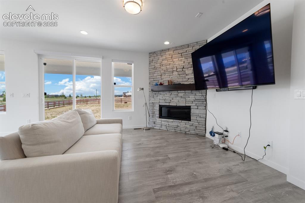 Image 20 of 38: Living space featuring light wood-finish flooring, a stone-clad fireplace w