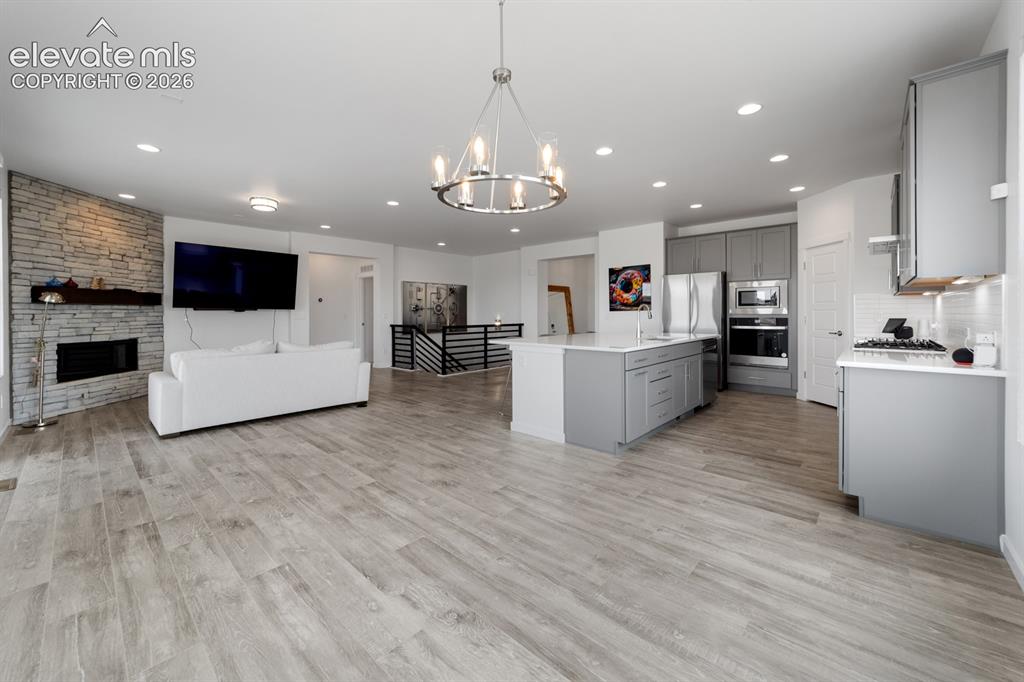 Image 21 of 38: Open-concept living space featuring wood-finish flooring, a stone accent fi