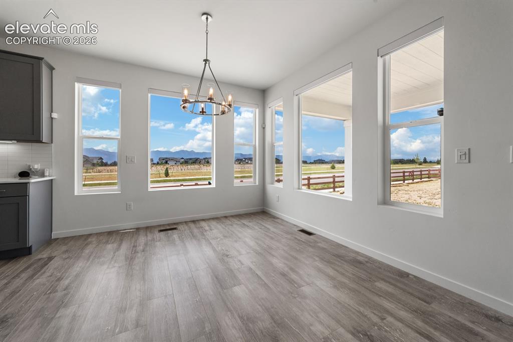 Image 23 of 38: Spacious room featuring multiple large windows, wood-finish flooring, a mod