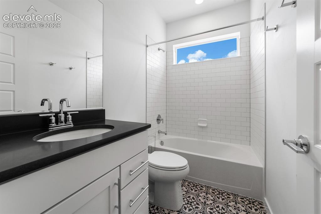 Image 28 of 38: Bathroom featuring a white vanity with a black countertop, chrome fixtures,