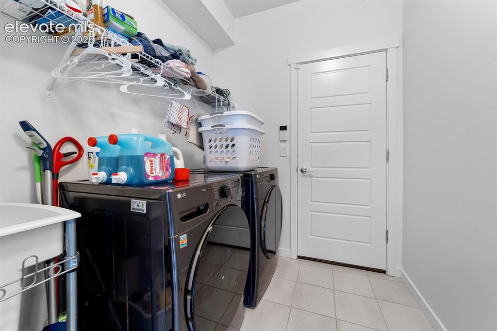 Image 29 of 38: Utility area featuring tile flooring, white walls, and a five-panel interio