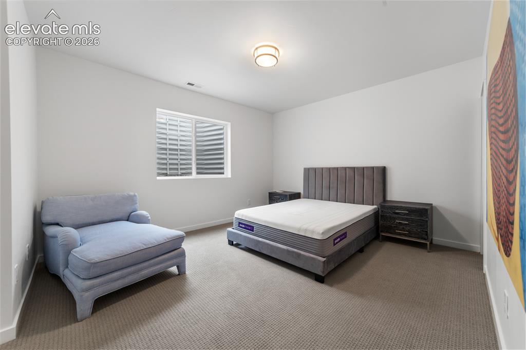 Image 31 of 38: Carpeted room with white walls, a single window with horizontal blinds, and