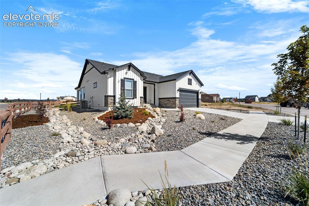Image 7 of 38: Contemporary exterior featuring white vertical siding and dark stone accent